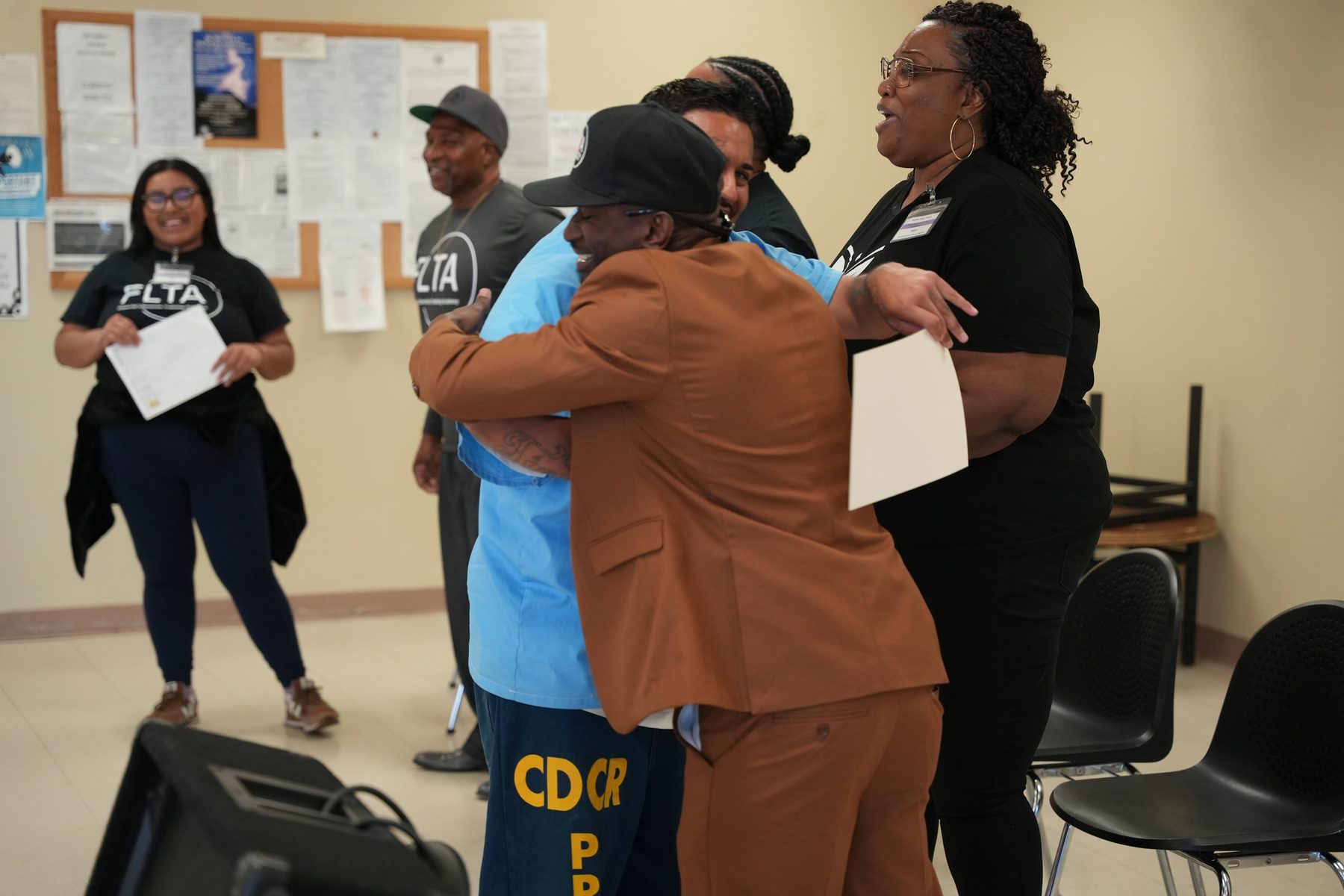 A graduate embraced at an FLTA Financial Reentry graduation inside Avenal State Prison